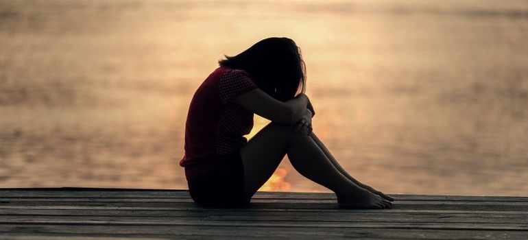 Woman sitting on the dock and hugging her knees.