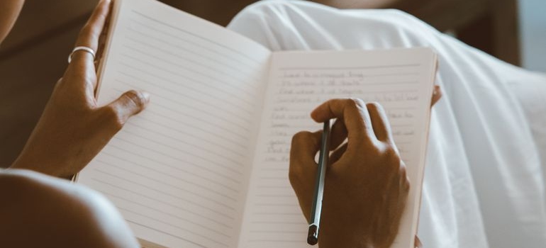 Person setting realistic goals in addiction recovery in a notebook.